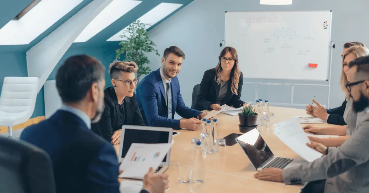 Business meeting around conference table with charts.